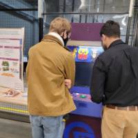 2 people in front of the arcade game pac man